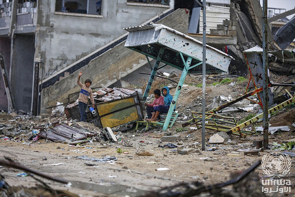 Children sitting on rubble of their destroyed home